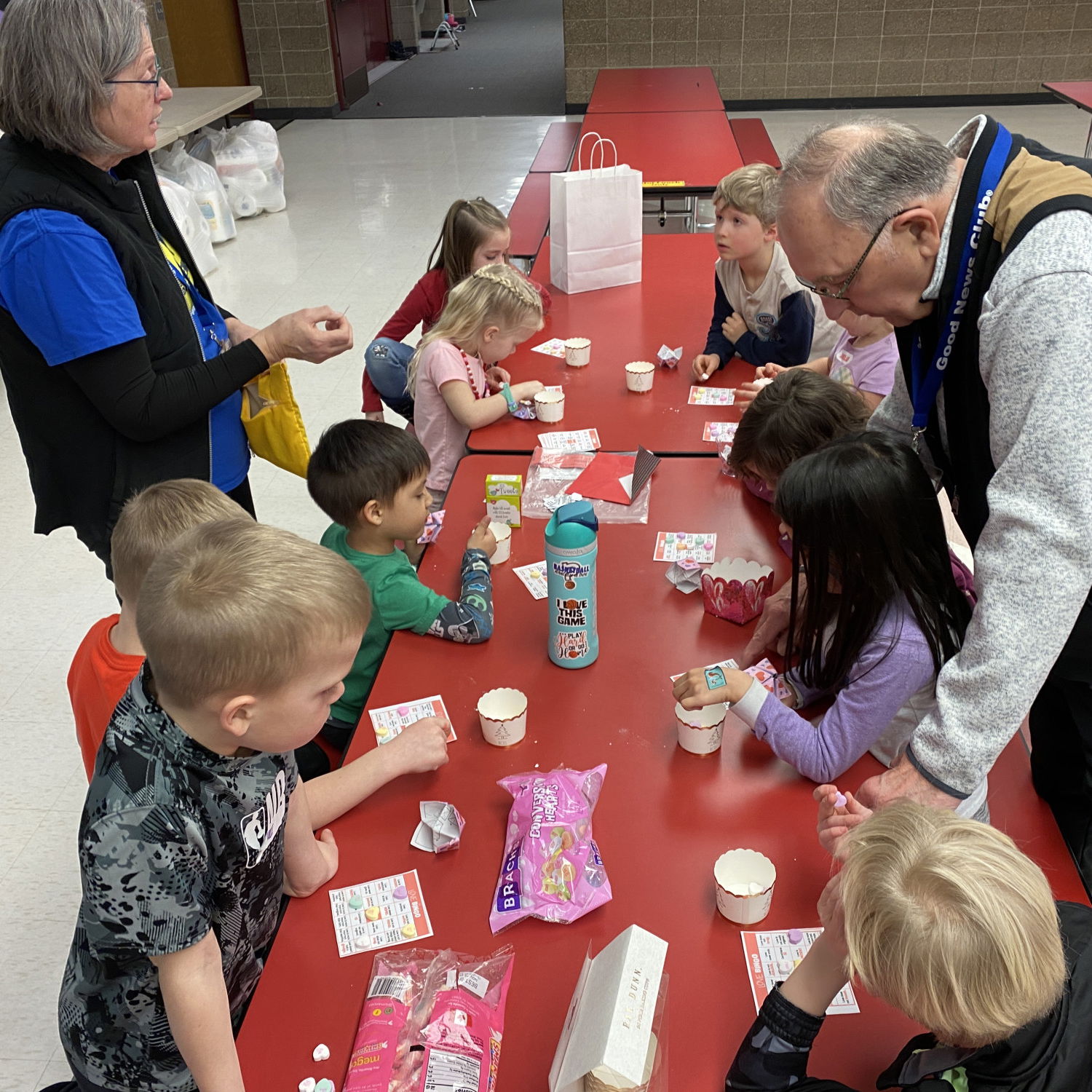 Children sitting at a red table doing activities