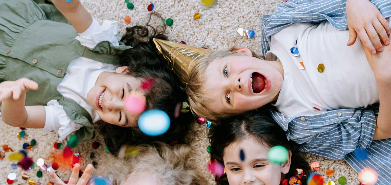 Children laying on the floor with confetti raining down on them